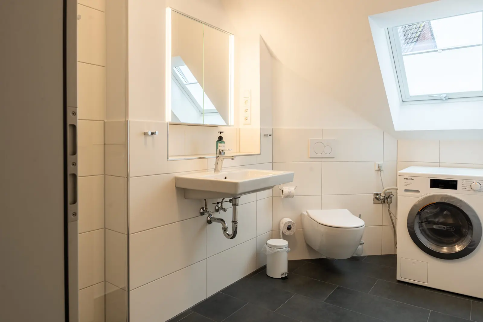 Badezimmer mit Dusche, Waschtisch und Waschmaschine