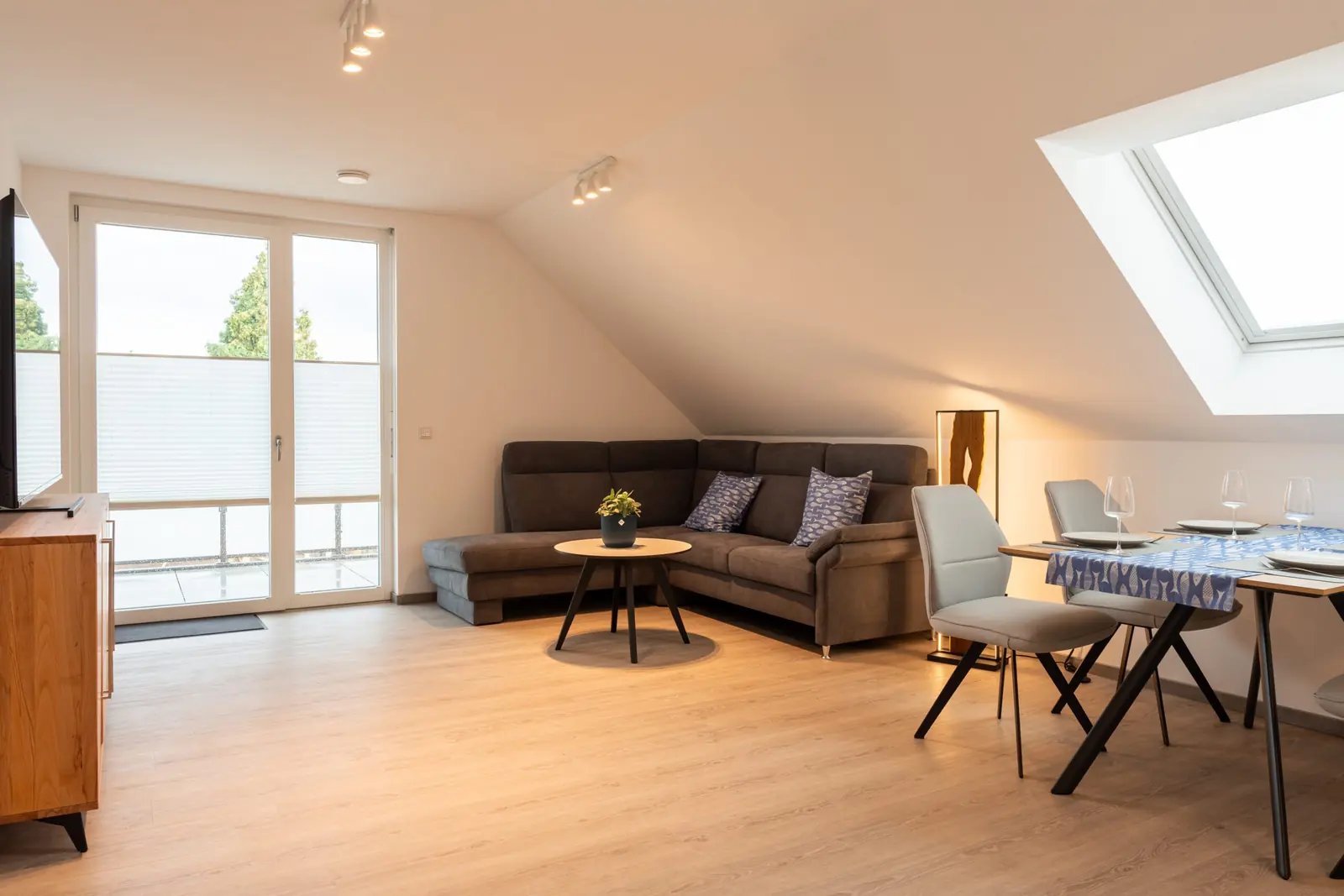 Heller Wohnbereich mit Ecksofa und Esstisch unter der Dachschräge